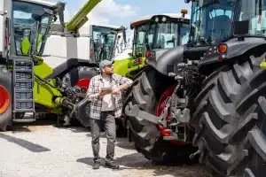 A man is considering his next tractor purchase at the dealership and weighing up the benefits of using equipment finance for the purchase