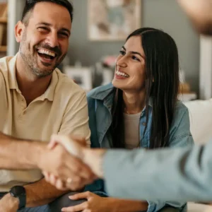 A young couple shake the hand of their loan broker after securing a much better interest rate and terms than the banks can offer