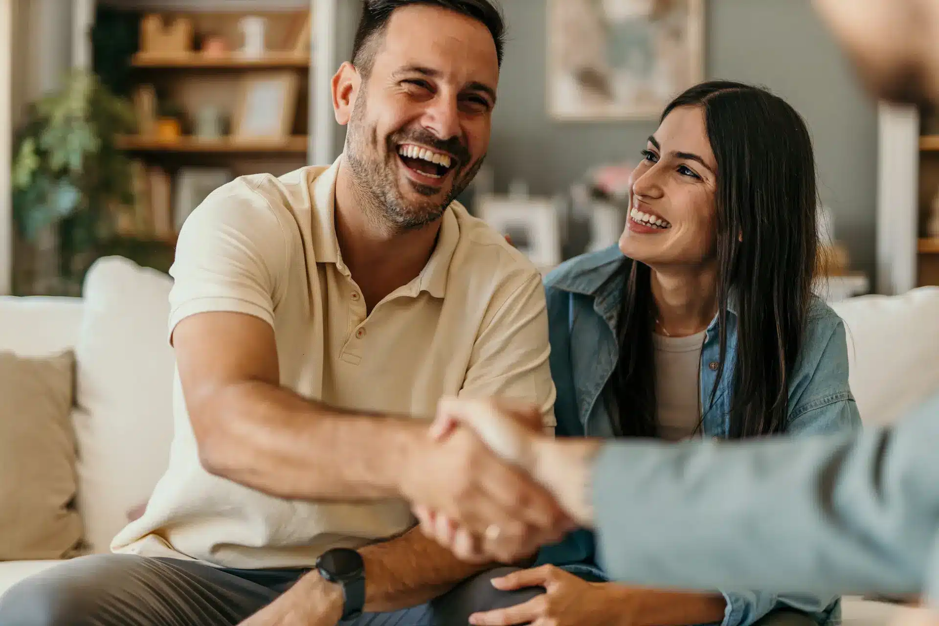 A young couple shake the hand of their loan broker after securing a much better interest rate and terms than the banks can offer