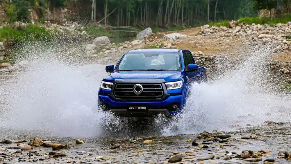 A blue GWM Cannon driving through a river crossing spraying water up while driving an offroad track