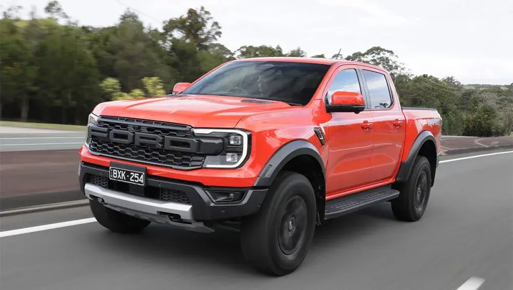 An orange Ford Ranger Raptor driving along a sealed highway