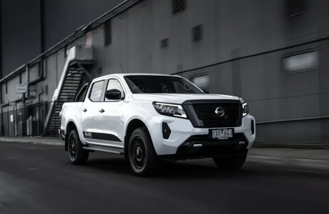 White Nissan Navara rolling along a sealed industrial back road