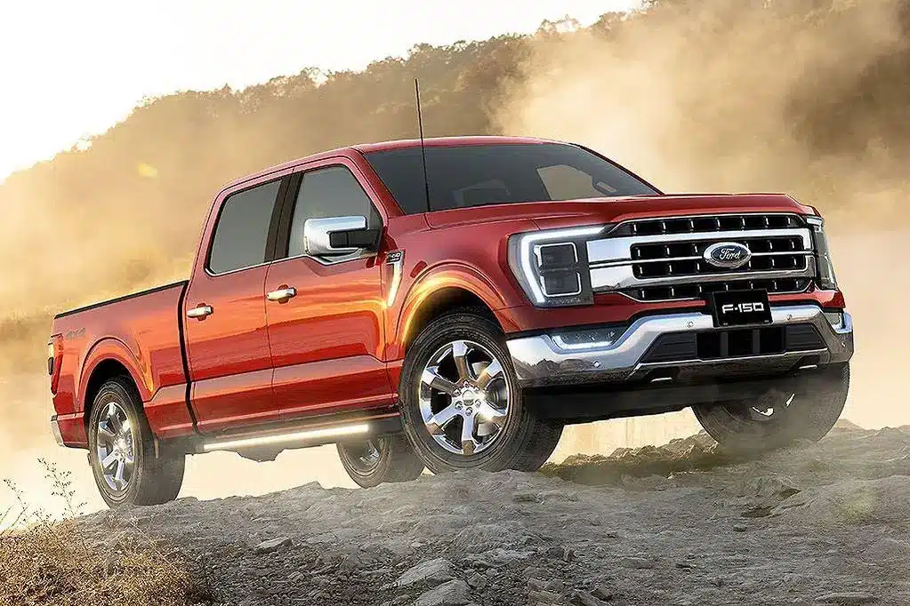 Red Ford F-150 parked on a little dirt slop surrounded by dust