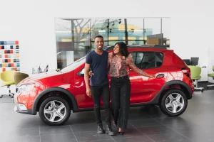 Young couple in a car showroom take delivery of their new car during a sale event