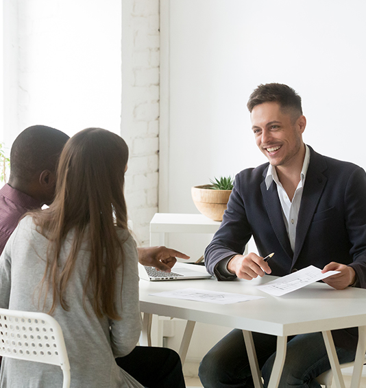 Smiling advisor meeting with diverse couple to discuss new home plans