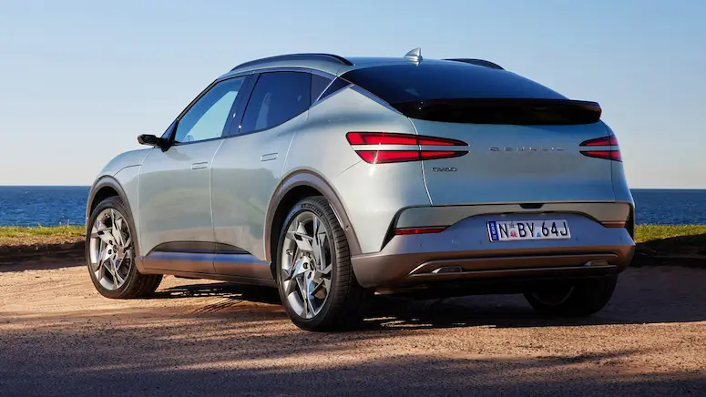 Light blue 2026 Genesis GV60 electric SUV with refined features parked by the ocean.