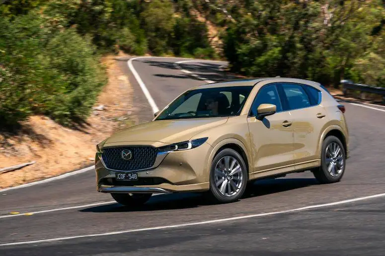 2026 Mazda CX-5 driving on a winding road, highlighting its refreshed styling and comfortable ride.